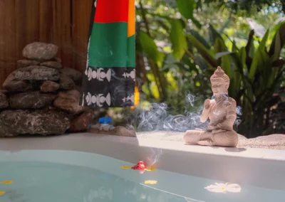 Serene outdoor bath area with Buddha statue and incense at Templo del Tigre.