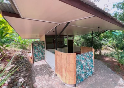 Exterior of jungle cabin at Templo del Tigre surrounded by tropical vegetation.