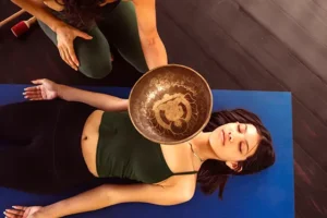 Retreat participant during a singing bowl sound healing session in the jungle yoga shala at Templo del Tigre near Corcovado National Park, Costa Rica.